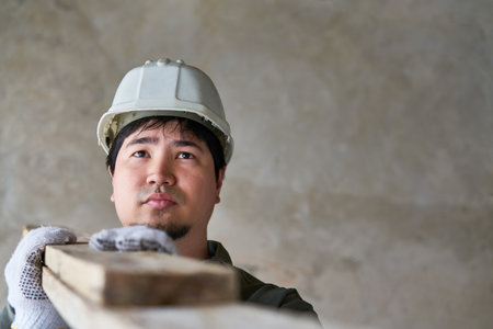 Male carpenter carrying planks on shoulder