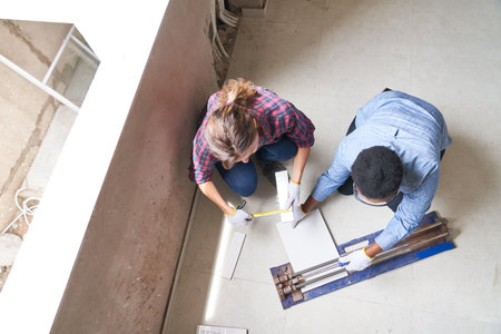 Female coworkers measuring and cutting plank