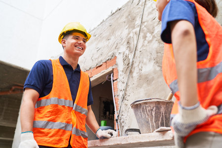 Smiling male mason discussing with female coworker