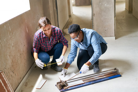 Female coworkers measuring and cutting plankの写真素材