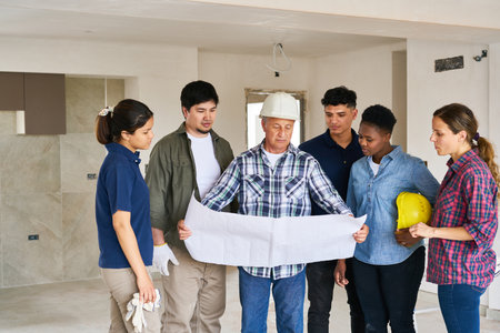 Contractor meeting over blueprint with coworkersの写真素材