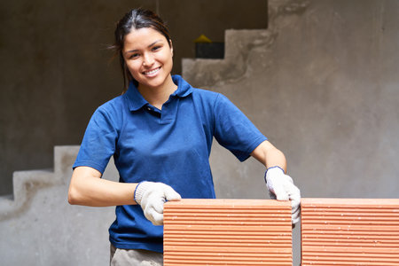 Smiling female bricklayer positioning brick on wall