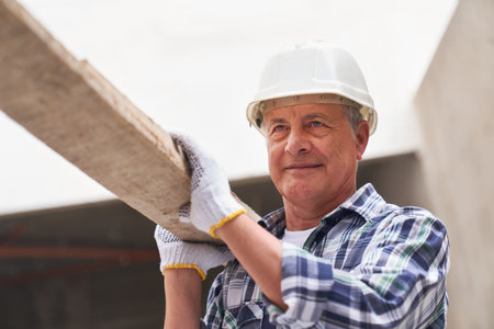 Senior male carpenter with planks on shoulder