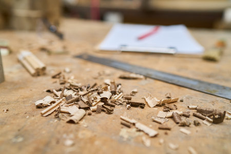 Detailed view of wood shavings scattered on a workbench in a carpentry shop, highlighting...