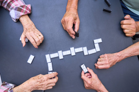 Elderly individuals engaging in a friendly game of dominoes, emphasizing social interaction and enjoyable moments in a group setting. The activity highlights companionship, recreation, and mental stimulation for senior citizens.の写真素材