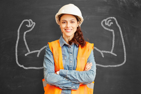 Young woman as a craftsman or architect in front of a blackboard with muscular arms as a competence...