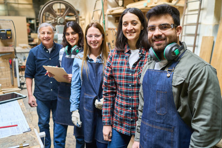 A diverse team of skilled lumberyard workers smiling confidently, showing teamwork and apprenticeship. They work together, blending experience and fresh perspectives in a dynamic, hands-on environment.の写真素材