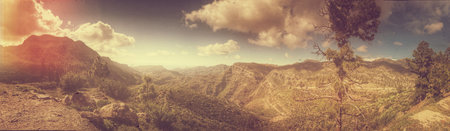 Expansive panoramic scene featuring stunning mountains, clear sky, and vibrant natural beauty.の写真素材