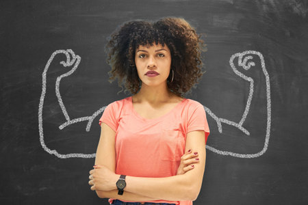 Young confident woman as an entrepreneur or student in front of a blackboard with muscular arms, representing the concept of career.の写真素材