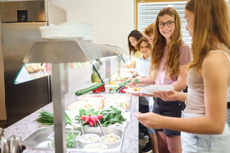 Young students selecting fresh and healthy food options in a clean school cafeteriaの写真素材