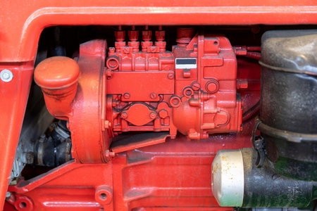A close-up shot shows the red engine block and fuel pump assembly of a tractor illustrating...