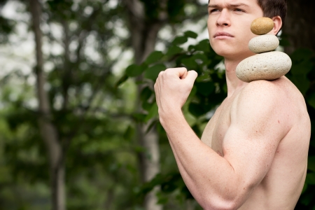 Strong athletic man holding a pile of stones in balance. Get the balance concept.の写真素材