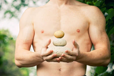 Strong athletic hand holding a pile of stones in balance. Get the balance concept.の写真素材