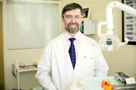 Portrait of happy middle-aged dentist in his cabinet, wearing lab coatの写真素材