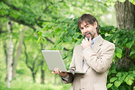 Portrait of happy middle-aged businessman holding notebook and smiling, outdoorsの写真素材