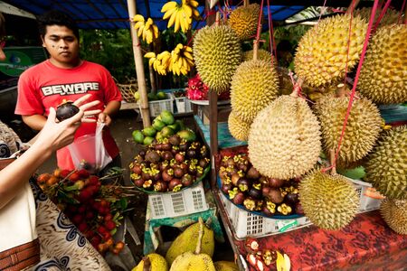 BALI - JANUARY 3  A man sells exotic fruits to local customers on January 3, 2013 in Bali, Indonesia  のeditorial素材