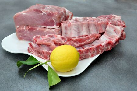 Tray with pork loin, ribs and a lemonの写真素材