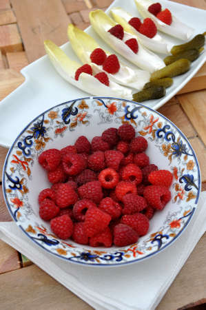 tray with pickles, raspberries and endives and bowl with raspberries