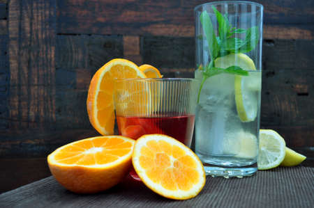 Glasses with refreshing drinks with fruits and herbs on an old wooden background