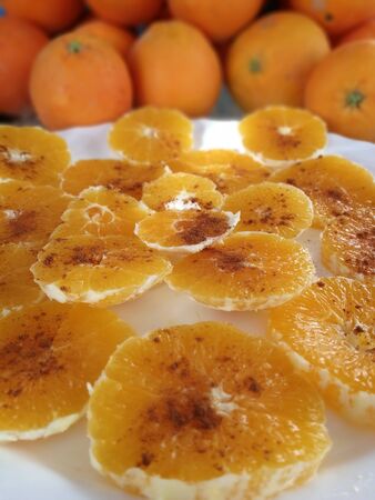 oranges slices with cinnamon on a white plateの写真素材