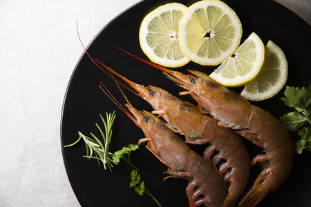 prawns and slices of lemon on a black plate