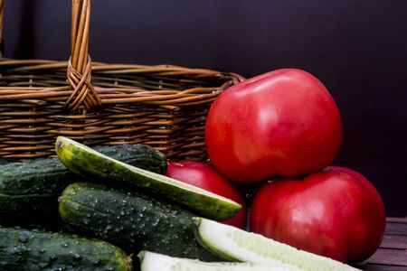 tomatoes and cucumbers next to a wicker basketの写真素材