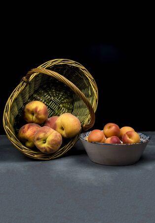 apricots on ceramic dish  and peaches on wicker basketの写真素材