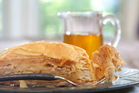 Baklava, delicious pastry dessert made with phyllo dough, nuts, butter and sugar served on a plate with a jar of honeyの写真素材