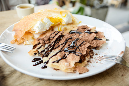Crepes with chocolate and whipped cream on wooden table, stock photoの写真素材