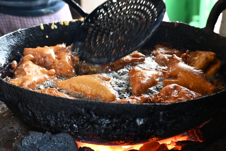Bread pakora is being fried in hot oil. It is made by stuffing the bread with potatoes and dipping it in the batter of chickpea flour and then frying it. popular snack of India.の写真素材