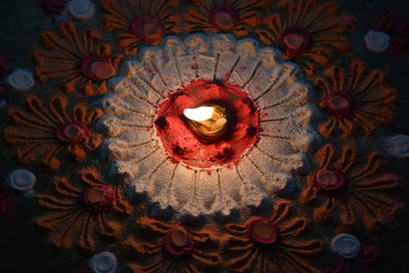 Beautiful rangoli design in vibrant colors. A small, lit diya or oil lamp  is placed at the center of the rangoli, casting a warm glow. colors festive and celebratory atmosphere.の写真素材