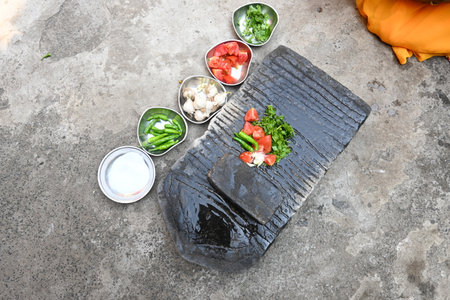 Grinding coriander chutney on stone grinder.
Grinding fresh coriander leaves with garlic, chillies,...