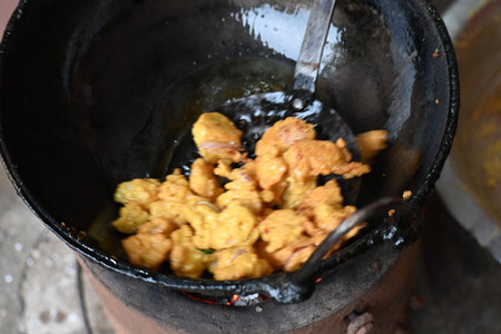 Onion pakora frying in iron pan. This is a popular street food in Indian subcontinent. Onion which...