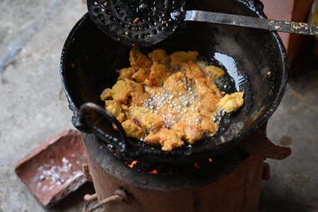 Onion pakora frying in iron pan. This is a popular street food in Indian subcontinent. Onion which...