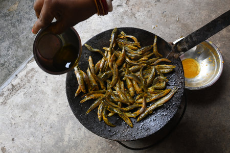 Small Snakehead or Channa orientalis Fish being fried in a pan. Its typically marinated with spices like turmeric, salt, and chili powder before being fried until they are crispy.の写真素材