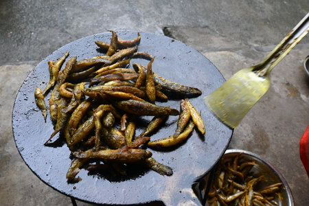Small Snakehead or Channa orientalis Fish being fried in a pan. Its typically marinated with spices like turmeric, salt, and chili powder before being fried until they are crispy.の写真素材