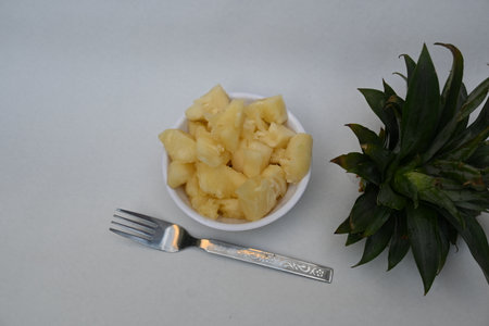 Pineapple or Ananas comosus slices on white background. It is aÂ tropical plantÂ with an edible fruit. It is plant in the familyÂ Bromeliaceae. Pineapple pieces in a bowl ready to eatの写真素材
