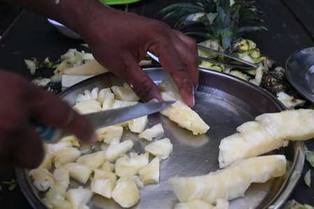 Pineapple or Ananas comosus chopping with knife. It is aÂ tropical plantÂ with an edible fruit....