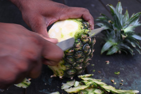 Peeling a Pineapple or Ananas comosus with knife. It is aÂ tropical plantÂ with an edible fruit....