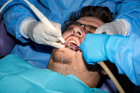 A man with a slight beard undergoing a dental procedureの写真素材