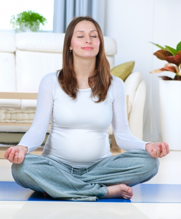 Beautiful Pregnant Woman Doing Yoga at Homeの写真素材