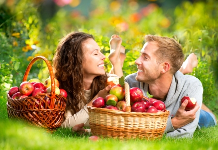 Couple Relaxing on the Grass and Eating Apples in Autumn Garden の写真素材