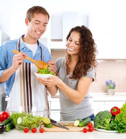Young Man Cooking  Happy Couple Eating Fresh Vegetable Salad の写真素材