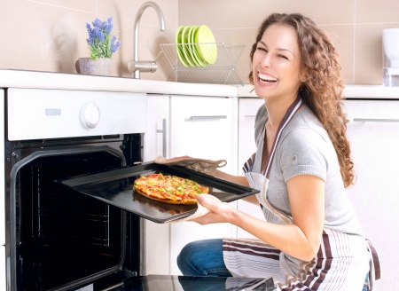 Happy Young Woman Cooking Pizza at Homeの写真素材