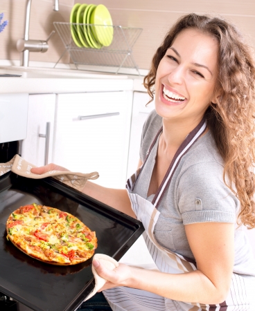 Happy Young Woman Cooking Pizza at Home の写真素材