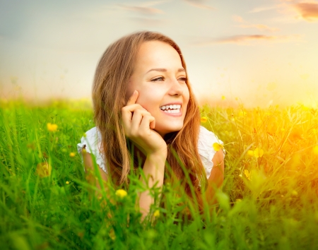 Beauty Girl in the Meadow lying on Green Grass with wild Flowersの写真素材