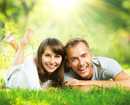 Happy Smiling Couple Together Relaxing on Green Grass Outdoor の写真素材