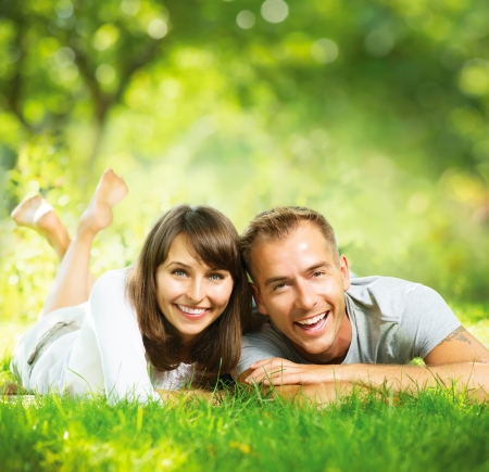 Happy Smiling Couple Together Relaxing on Green Grass Outdoor の写真素材