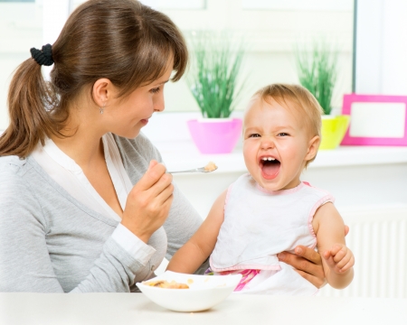 Mother Feeding Her Baby Girl with a Spoon の写真素材