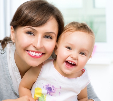 Happy Smiling Mother and Baby kissing and hugging at Home